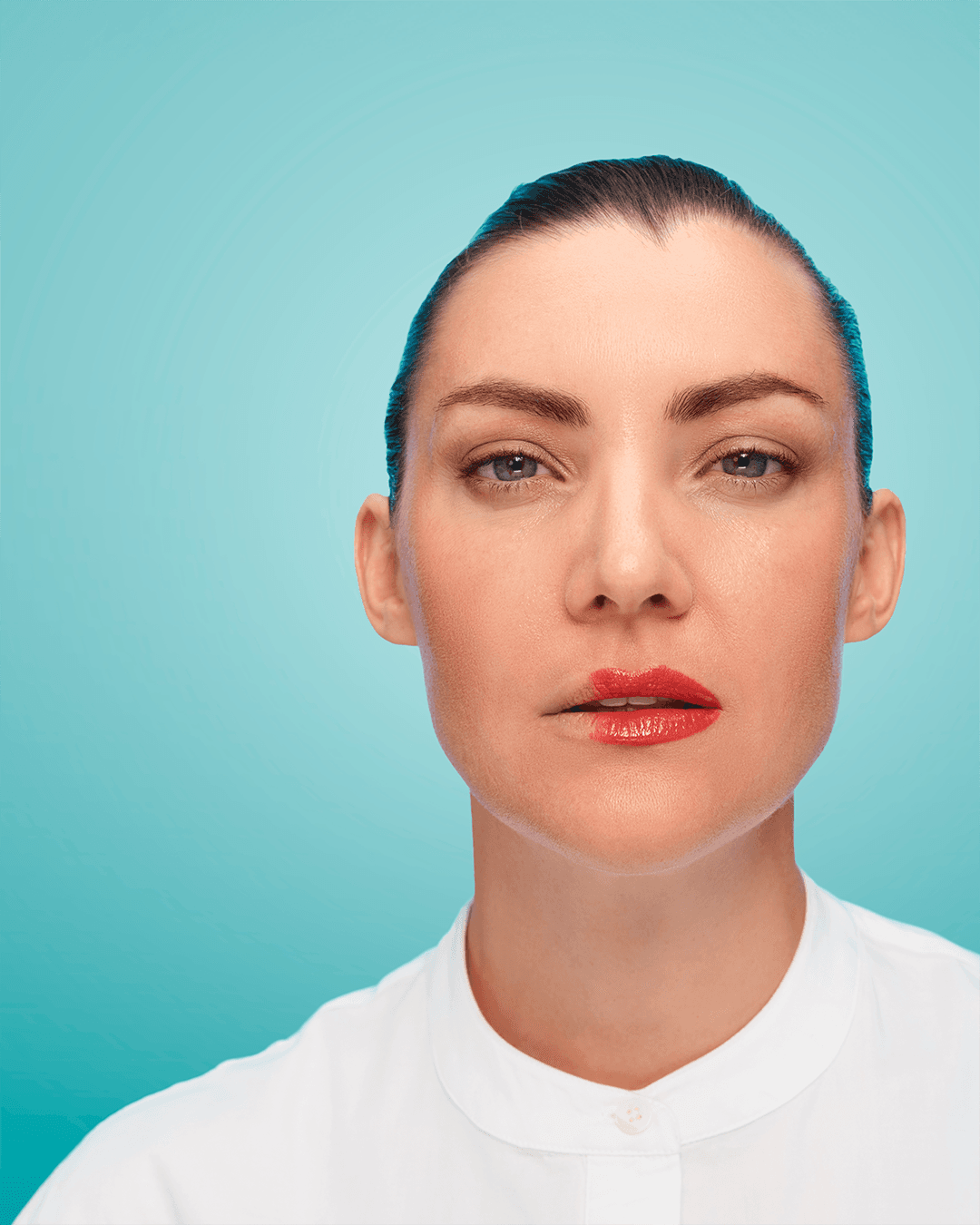 Blue background, a woman in a white shirt and red lipstick is looking into the camera