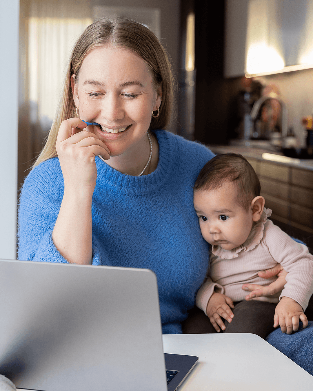A multitasking mom holding her baby on one arm and cleaning between her teeth at the same time