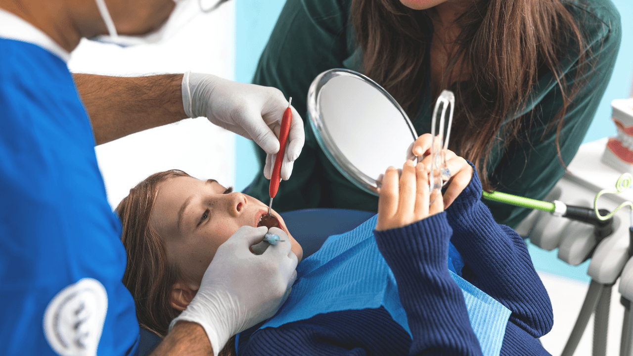 Dentist showing a young patient how to brush her teeht