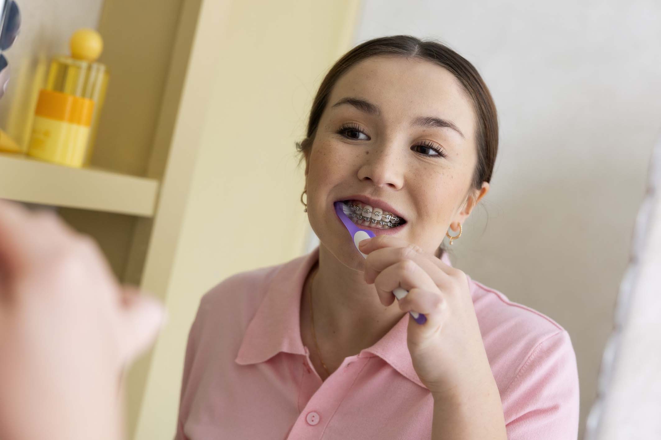 Young girl with braces brushing her teeth